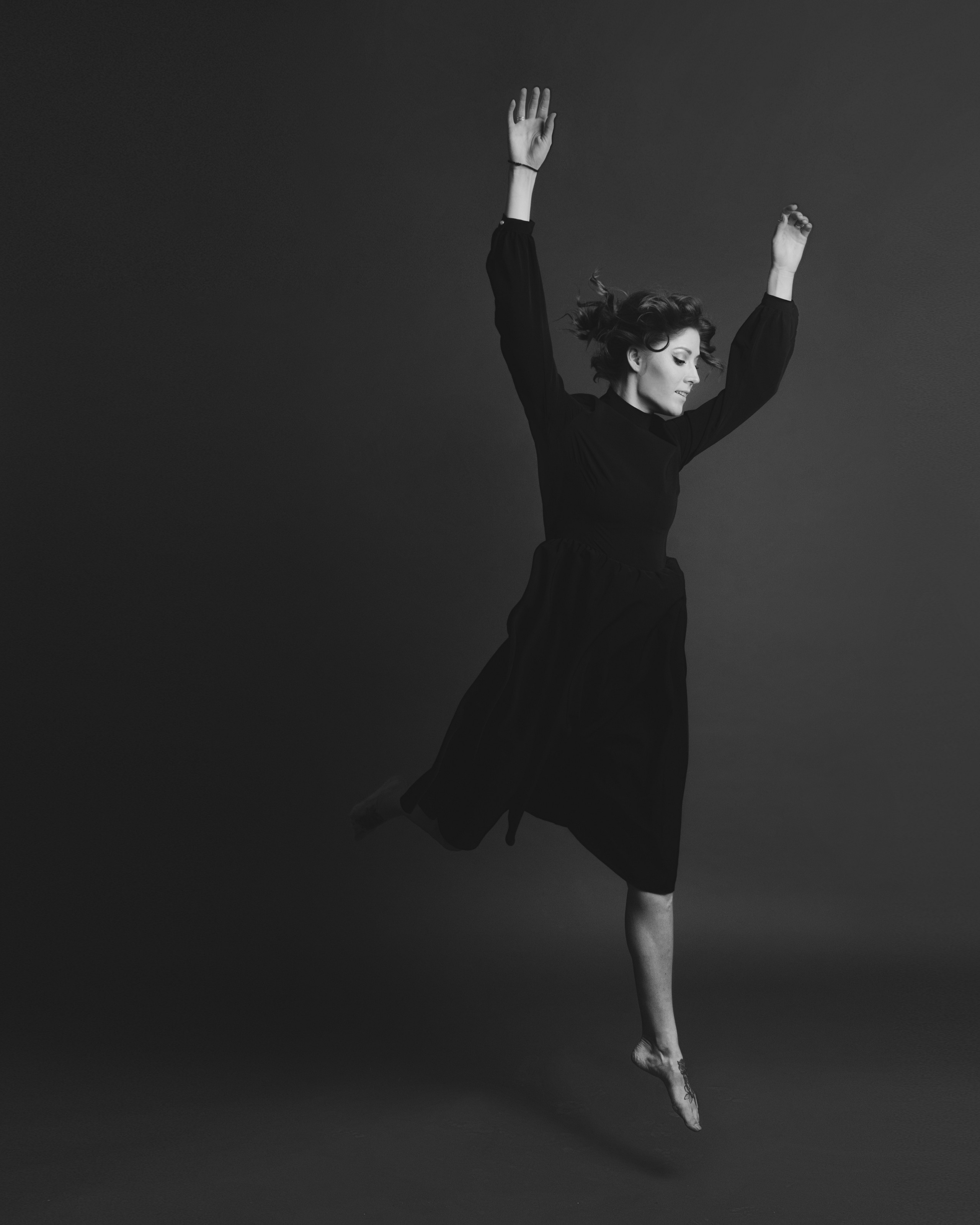 A woman in black dress taking a leap towards … somewhere